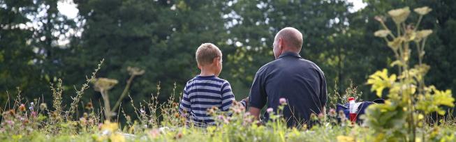 Barn og voksen der sidder sammen i naturen