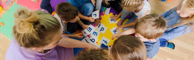 Pædagog og børn der leger med bogstaver