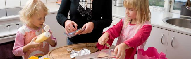To børn der smørrer madpakke med en voksen