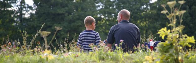 Barn og voksen sidder i naturen